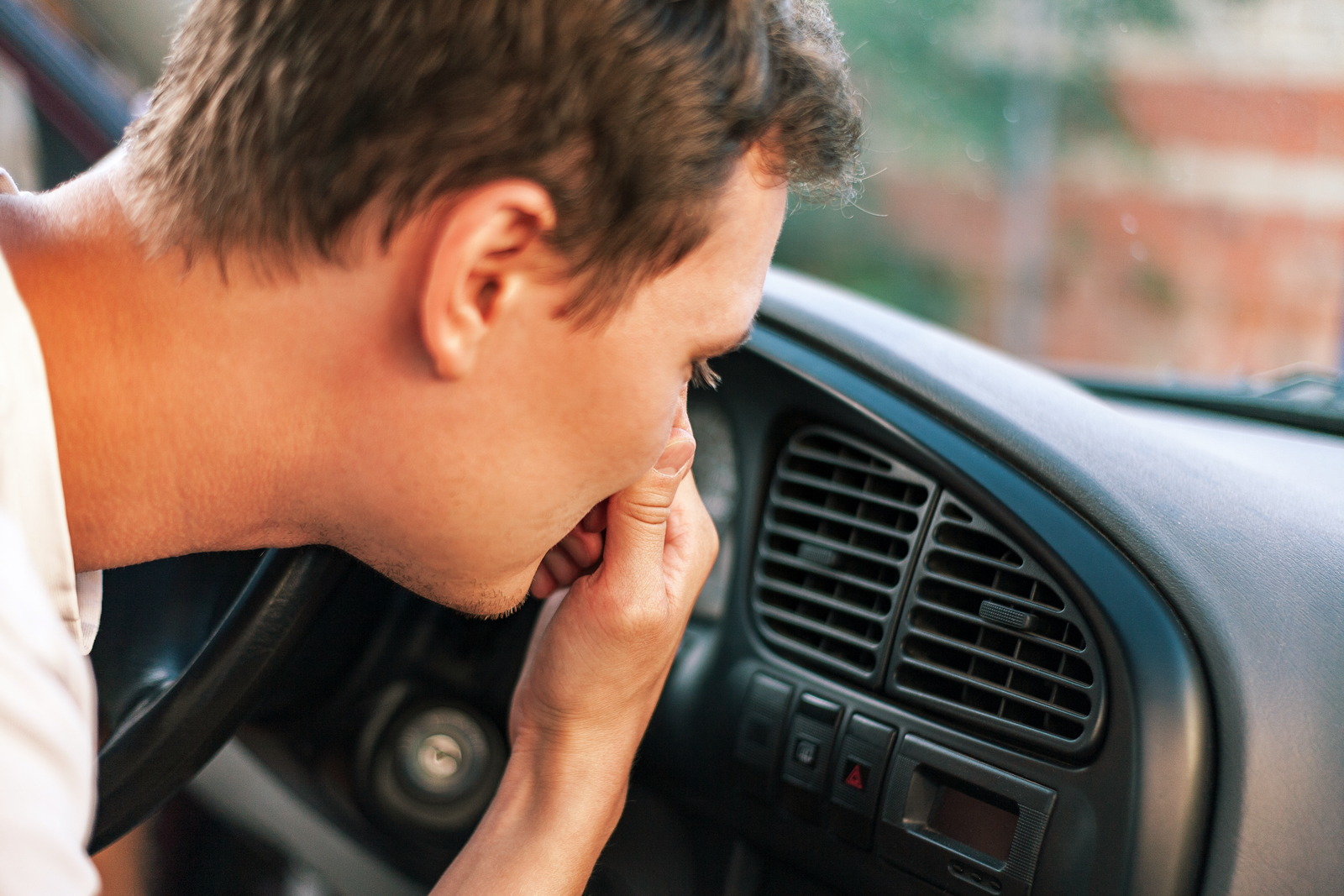Man holding nose in car