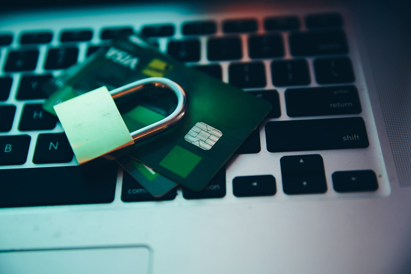 Credit cards and a lock sitting on a computer.